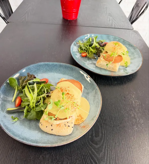 Two plates of vegan eggs benedict with hollandaise and salad