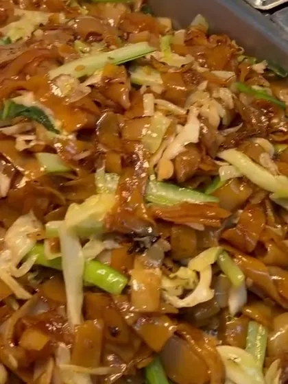 Tray of wok-fried flat rice noodles with cabbage and spring onion