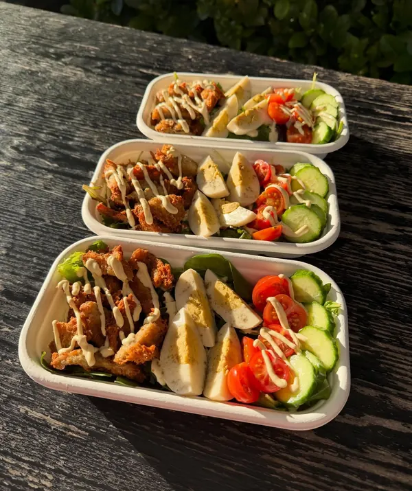 Takeaway salad boxes with crispy bites, vegan egg, tomato and cucumber